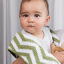 A cute baby looking forward while wrapped snugly in a soft, cozy Sage Chevron Knitted Chenille Blanket.