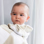 Close-up of a baby resting comfortably on a parent's shoulder, wrapped in a cozy Taupe Check Knitted Chenille Blanket.