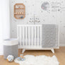 Wide view of a gray and white sheep-themed nursery featuring a white baby crib, coordinating storage bin, matching blanket, and the hanging musical mobile.