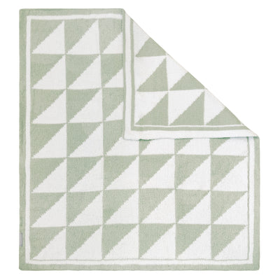 Flat lay studio view of the Chenille Baby Blanket in Sage Triangle style, showing a soft sage green and cream geometric half-square triangle pattern with a folded corner revealing the neat, reversible knit design.