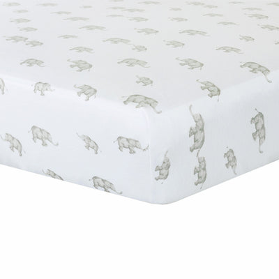 Close-up studio shot of the Cotton Jersey Fitted Sheet in Elephant Heritage style, highlighting the deep corner pocket fit and a clean white fabric pattern printed with grey elephant silhouettes.