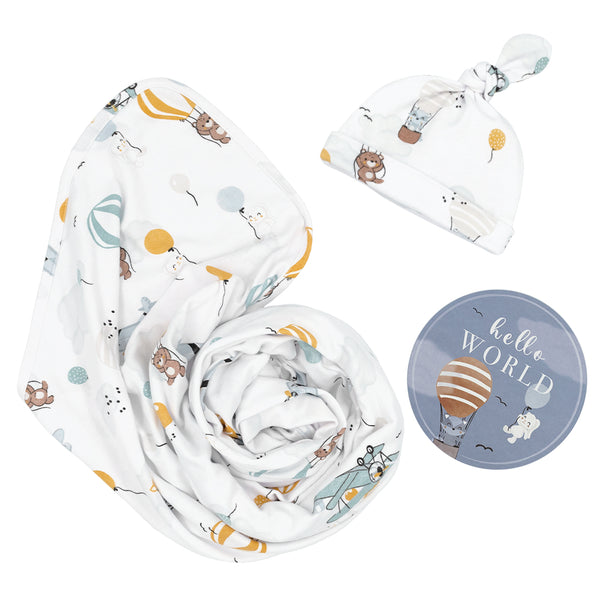 Hello World 3-piece newborn gift set in Up And Up Away style, featuring a soft cotton jersey swaddle blanket and matching knotted baby beanie with a colorful hot air balloon and airplane print, alongside a round milestone disc.