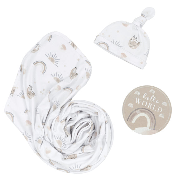 Hello World 3-piece newborn gift set in Rainbow Sloth style, featuring a soft white jersey cotton swaddle blanket, a matching printed top-knot baby beanie, and a round taupe milestone announcement disc.
