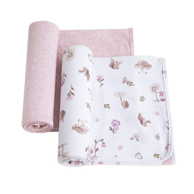 2-pack baby jersey swaddle blanket set in Mushroom House style, showcasing one rolled wrap with a soft pink botanical print and another partially unrolled featuring whimsical mushroom and woodland animal illustrations.