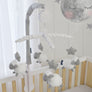 Close-up view of the hanging plush sheep and stars of the Musical Mobile installed on a light wood baby crib.