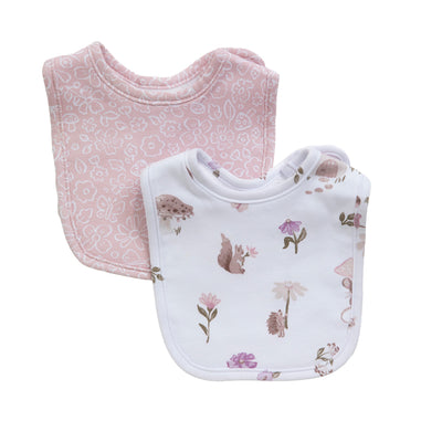 Flat lay view of the Mushroom House 2-piece bib set, showcasing one bib with a soft pink botanical pattern and the second with whimsical mushroom house and wildflower illustrations.