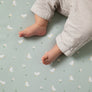 Detail shot of a baby's bare feet kicking on a soft, breathable Little Geese Cotton Jersey Fitted Sheet.