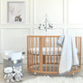 Close-up view of the hanging plush sheep and stars of the Musical Mobile installed on a light wood baby crib.