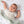 Happy baby lying down and covered comfortably with the cozy Goosey Goosey Jersey Sherpa Blanket on a matching printed crib sheet.