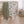 High-angle nursery view showing both the olive green dot and white woodland animal jersey swaddle blankets draped over the side of an oval wooden crib.