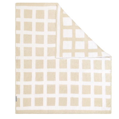 Flat lay studio view of the Chenille Baby Blanket in Cream Check style, showcasing a plush cream and tan windowpane grid pattern with a folded corner revealing the neat, reversible knit structure.